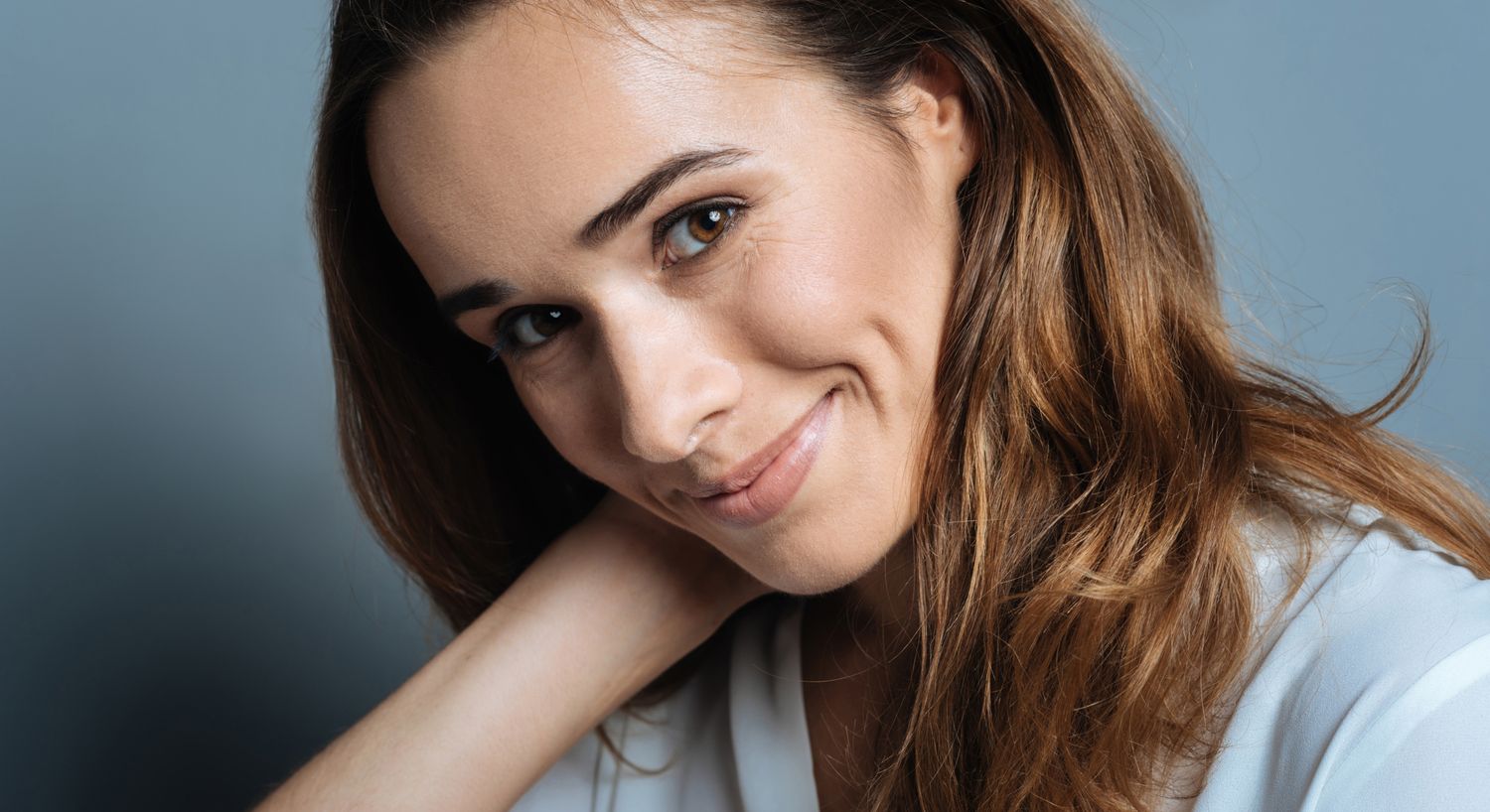 Smiling woman with long hair and soft expression.